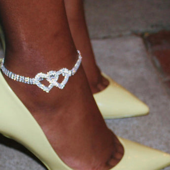 Heart-shaped diamond bridal anklet adorning a woman's ankle, elegant wedding foot jewelry with a sparkling charm.
