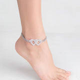 Heart-shaped diamond bridal anklet adorning a woman's bare foot, highlighting elegant wedding foot jewelry.