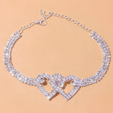 Heart-shaped diamond bridal anklet featuring elegant silver design on a bride's foot, showcasing intricate jewelry craftsmanship.