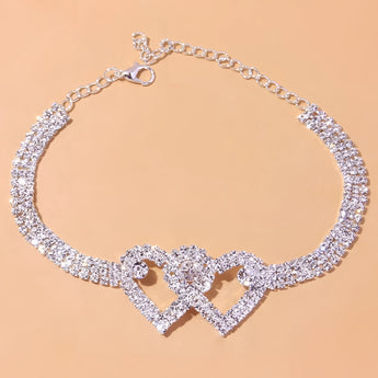 Heart-shaped diamond bridal anklet featuring elegant silver design on a bride's foot, showcasing intricate jewelry craftsmanship.