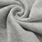 Heather grey women's lightweight casual pullover hoodie laid on a flat surface, featuring long sleeves and a soft fabric texture, surrounded by patterned linens and small decorative plants.