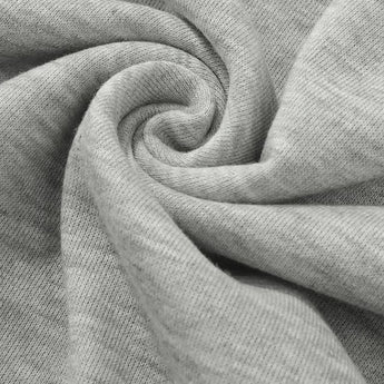 Heather grey women's lightweight casual pullover hoodie laid on a flat surface, featuring long sleeves and a soft fabric texture, surrounded by patterned linens and small decorative plants.