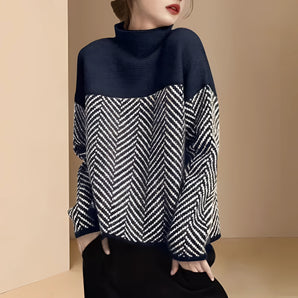 
A black oversized chevron-patterned wool blend sweater with a high neck design, worn by a woman and showcasing long sleeves and a loose, comfortable fit suitable for winter fashion.