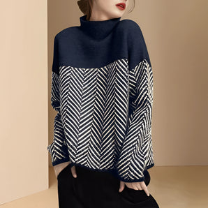 Marine blue high-neck wool sweater featuring a chevron pattern, with black and white accents, displayed on a mannequin showcasing the long sleeves and fitted waist design.
