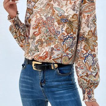 High-neck paisley blouse in a bohemian style, featuring a white fabric with intricate patterns, long sleeves, and a stylish autumn design. The blouse is worn by a model with shoulder-length hair, showcasing the fashionable and elegant look of the top.