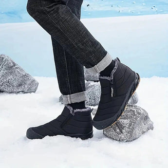 High-Traction Anti-Slip Rubber Sole Athletic Sneakers worn by a person standing in the snow, with visible denim jeans and part of the leg, showcasing the shoe's grip and suitability for cold weather sportswear.