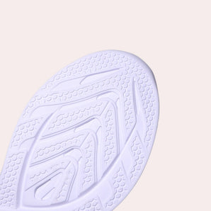 A pair of high-traction women's sneakers featuring a durable non-slip sole, showcased against a patterned background with shades of electric blue and wooden accents.