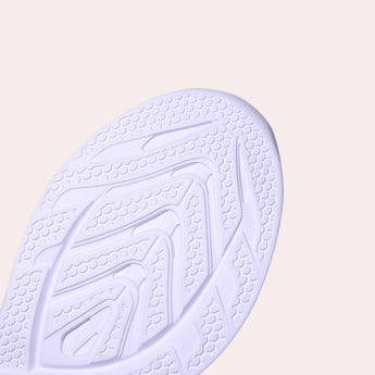 A pair of high-traction women's sneakers featuring a durable non-slip sole, showcased against a patterned background with shades of electric blue and wooden accents.