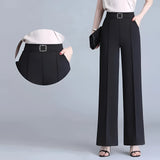 Wide-leg black trousers with a high waist, styled for formal business occasions, paired with a grey dress shirt.