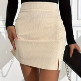A stylish woman wearing a high waist ribbed mini skirt in a casual chic autumn fashion, with a black and white ensemble featuring a white dress shirt. Her arms are partially visible, and she appears to be posing against a neutral background.
