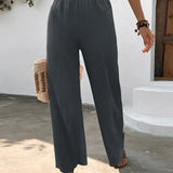 Woman wearing high-waisted pleated pink trousers, standing with hands in pockets, showcasing lightweight summer fabric and tailored fit around waist, thighs, and knees.