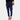 A woman wearing high-waisted white tailored trousers paired with a marine blue top, showcasing the chic ivory pants that highlight the waist and extend down to create an elegant silhouette.