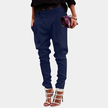 A woman wearing high-waisted white tailored trousers paired with a marine blue top, showcasing the chic ivory pants that highlight the waist and extend down to create an elegant silhouette.