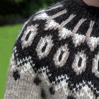 Icelandic wool sweater featuring a Nordic pattern in shades of grey, showcasing long sleeves and a cozy, woolen texture suited for unisex winter wear.