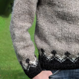 Unisex Icelandic wool sweater featuring a Nordic pattern, with visible sleeves and a cozy woolen texture, worn by a person standing on grass while wearing denim jeans.