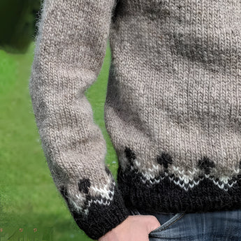 Unisex Icelandic wool sweater featuring a Nordic pattern, with visible sleeves and a cozy woolen texture, worn by a person standing on grass while wearing denim jeans.