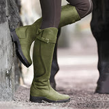 Insulated waterproof leather riding boots in green, size 43, shown worn by a person standing on grass. The knee-high boots are paired with denim jeans, highlighting their thermal design suitable for winter equestrian activities.