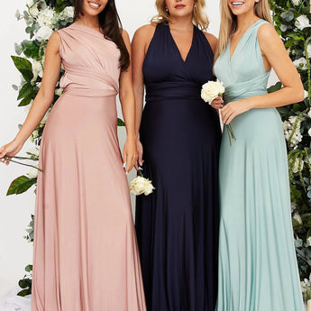 Ivory backless bridesmaid maxi dress featuring crossover straps and pockets, worn by a smiling woman with shoulder-length hair.
