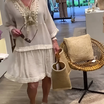 Ivory boho chic lace trim tunic dress in a lightweight fabric featuring a neutral color, worn by a model with long hair. The dress includes stylish sleeve details and a defined waist, embodying a comfortable and fashionable summer style.