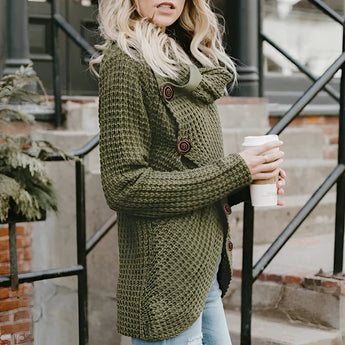 
An ivory chunky knit sweater featuring a buttoned cowl neckline, oversized design, and long sleeves, modeled by a standing person.