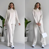 Ivory ribbed knit sweater and pants set displayed on a mannequin, showcasing the monochrome knitwear design with long sleeves and a high neckline.