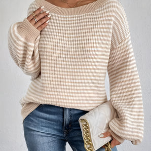Ivory and apricot striped oversized knit sweater featuring a boat neck design, worn by a woman. The sweater is styled as a relaxed pullover with a loose fit, highlighting the shoulders and arms.