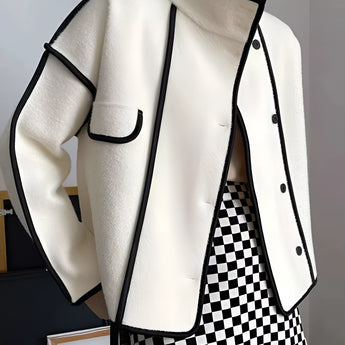 Ivory wool jacket with black trim, featuring a double-breasted design and a high collar, displayed on a mannequin. The jacket includes shoulder detailing and long sleeves.