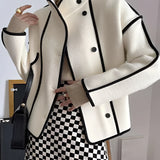 Ivory wool jacket with black trim, featuring a double-breasted design and a high collar. The jacket has long sleeves and structured shoulders, offering a stylish and formal appearance.