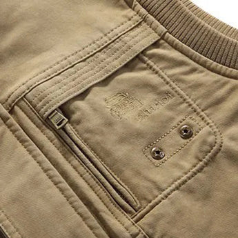 Men's lightweight khaki bomber jacket featuring a ribbed collar and snap button closure, displayed against a neutral background. The jacket has long sleeves and is made from a textile material in a khaki-beige color.