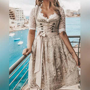 Lace embroidered dirndl dress in khaki, featuring a traditional Bavarian design with intricate lace detailing. The dress is a one-piece garment with short sleeves and a fitted waist, showcasing a stylish and elegant look suitable for Oktoberfest. The model is standing, highlighting the dress's form and craftsmanship.