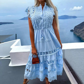 Blue lace tiered maxi dress with crochet details, designed as a boho summer resort wear piece, displayed against a sky background.