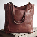 Rich brown handmade leather tote bag for women, designed for work use. The large rectangular tote features shoulder straps and a spacious interior, showcasing a classic and elegant style.