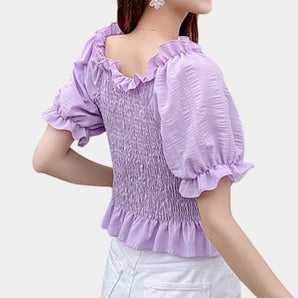 Lavender smocked crop top with puff sleeves and ruffled blouse design in a vibrant purple hue.
