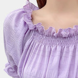 Lavender smocked crop top with puff sleeves and ruffle detailing, showcasing a feminine and stylish design in a light purple fabric.