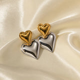Layered dual-tone heart dangle earrings with silver and gold tones, featuring intricate metal design.