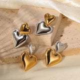 Layered dual-tone heart dangle earrings in silver and gold.