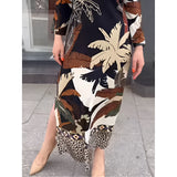 Leaf print long sleeve midi dress with nature-inspired design, featuring a fitted waist and flowy skirt, modeled outdoors with sunglasses.