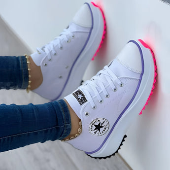 White LED sneakers for women with neon sole, worn by a person wearing jeans.
