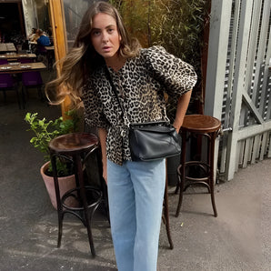 Leopard print animal top with long sleeves, worn by a person with an autumn casual street style, accessorized with sunglasses and a sleek hairstyle.