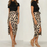Leopard print high-waist midi skirt worn by a woman, showcasing a trendy and fashionable look. The outfit is complemented with stylish accessories such as eyewear and paired with footwear. The image highlights the skirt's length and pattern, emphasizing its appeal in women's fashion.