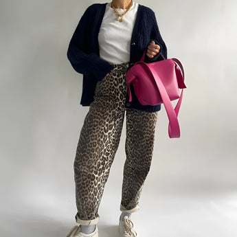A person wearing leopard print jeans paired with a casual top, accessorized with sunglasses and trendy footwear, embodying a chic street style look.