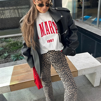 Leopard print jeans modeled by a person wearing sunglasses and a cap, showcasing a trendy street style look.