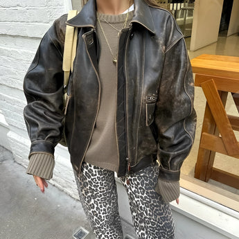 Leopard print jeans featuring a trendy animal print design, styled with a grey leather jacket and a collared shirt.