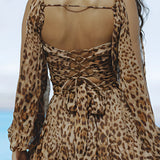 Leopard print open back mini dress featuring elegant pearl accessories, with long sleeves and a fitted waist, designed for a stylish and fashionable look.