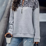 Woman wearing a gray pullover with a leopard print quilted half-zip design, showcasing chic streetwear style.
