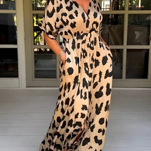Leopard Print V-Neck Maxi Dress with elegant summer beachwear design featuring a flowing silhouette. The dress includes short sleeves and is styled with a deep V-neckline. The model is wearing matching footwear and accessories, showcasing a chic and sophisticated look.