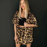 Leopard print women's suit featuring a trendy blazer and skirt set worn by a model. The outfit showcases a stylish leopard print design with a tailored blazer and a matching skirt, emphasizing the model's waist and legs.