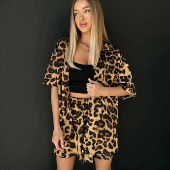 Leopard print women's suit featuring a trendy blazer and skirt set worn by a model. The outfit showcases a stylish leopard print design with a tailored blazer and a matching skirt, emphasizing the model's waist and legs.