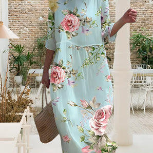 Light blue floral midi dress featuring a chic summer fashion design, showcasing delicate white and green floral patterns. The dress is a one-piece garment with a stylish neckline and shoulder detail.
