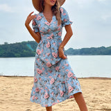 Light blue floral midi dress with a V-neck and short sleeves, worn by a person outdoors with a blue sky and clouds in the background.